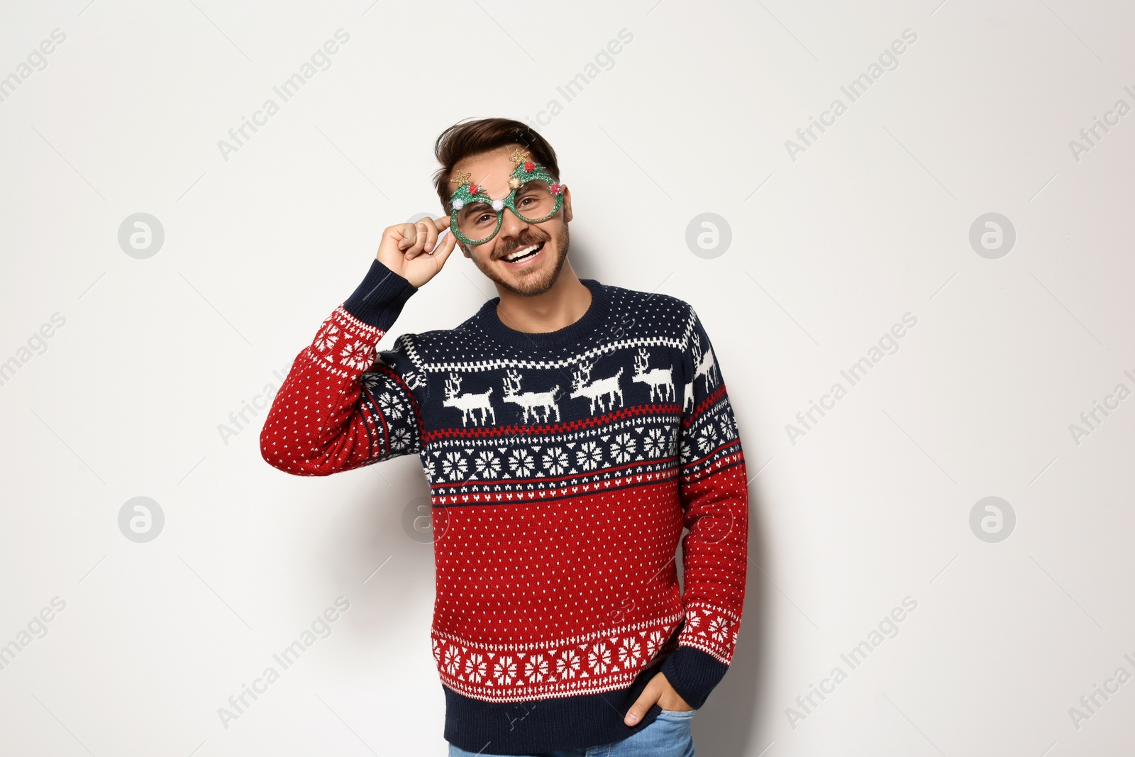 Photo of Young man in Christmas sweater with party glasses on white background