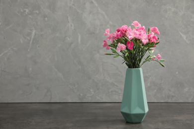 Vase with beautiful carnations on grey background. Space for text