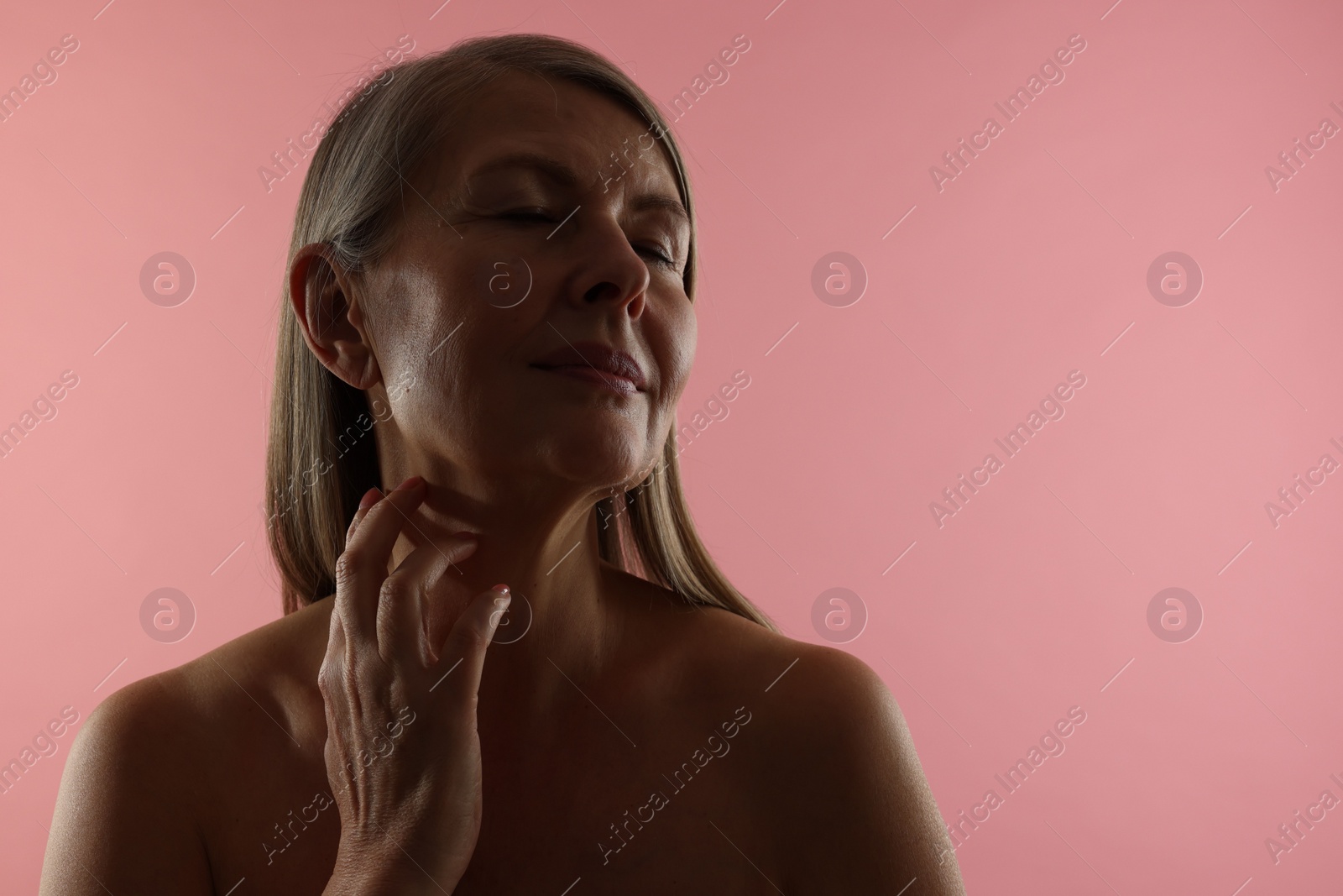 Photo of Beautiful woman touching her neck on pink background, space for text