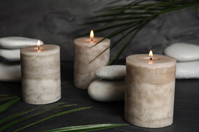 Burning candles and spa stones on dark table