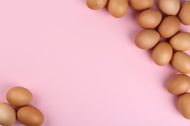 Photo of Raw chicken eggs on pink background, flat lay. Space for text