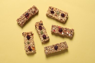 Photo of Tasty granola bars on yellow background, flat lay
