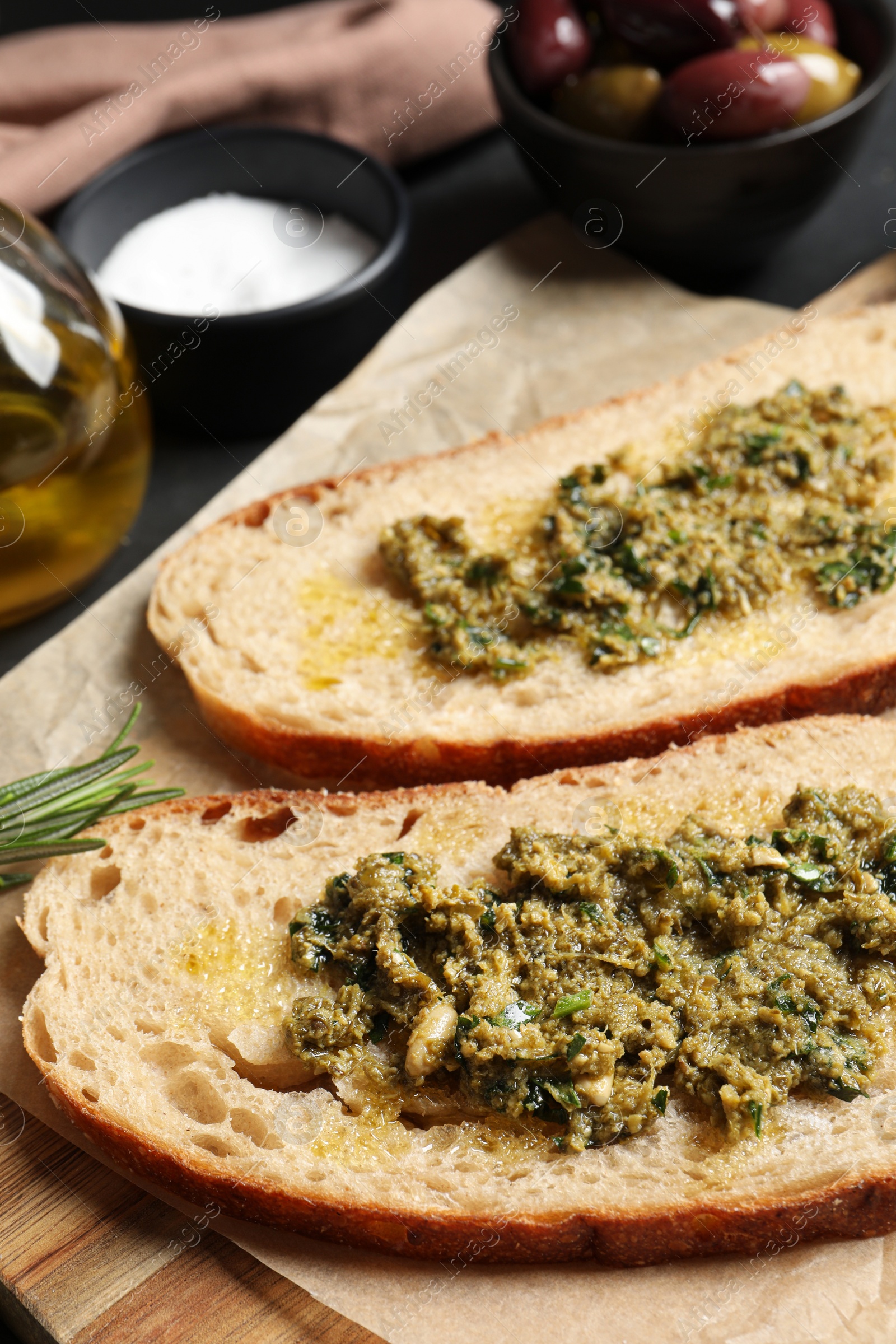 Photo of Tasty bruschettas with pesto on wooden board, closeup