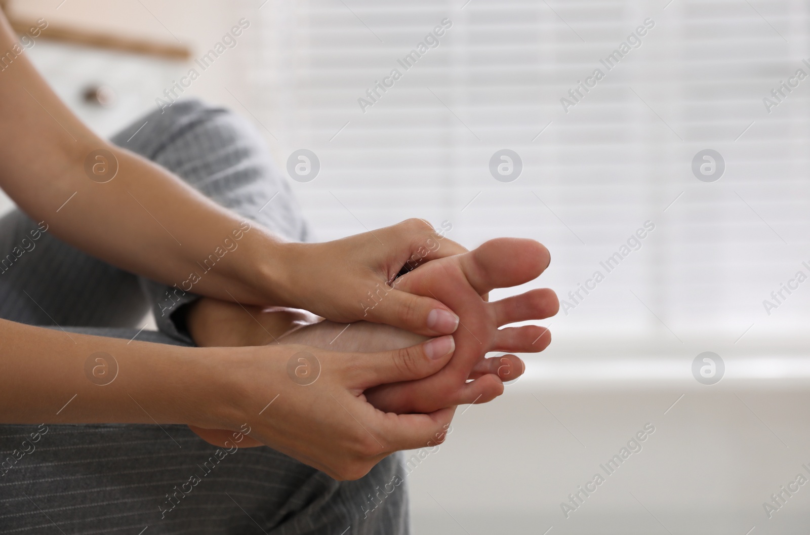 Photo of Young woman suffering from foot pain indoors, closeup