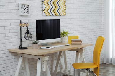 Stylish home office interior with comfortable workplace near white brick wall