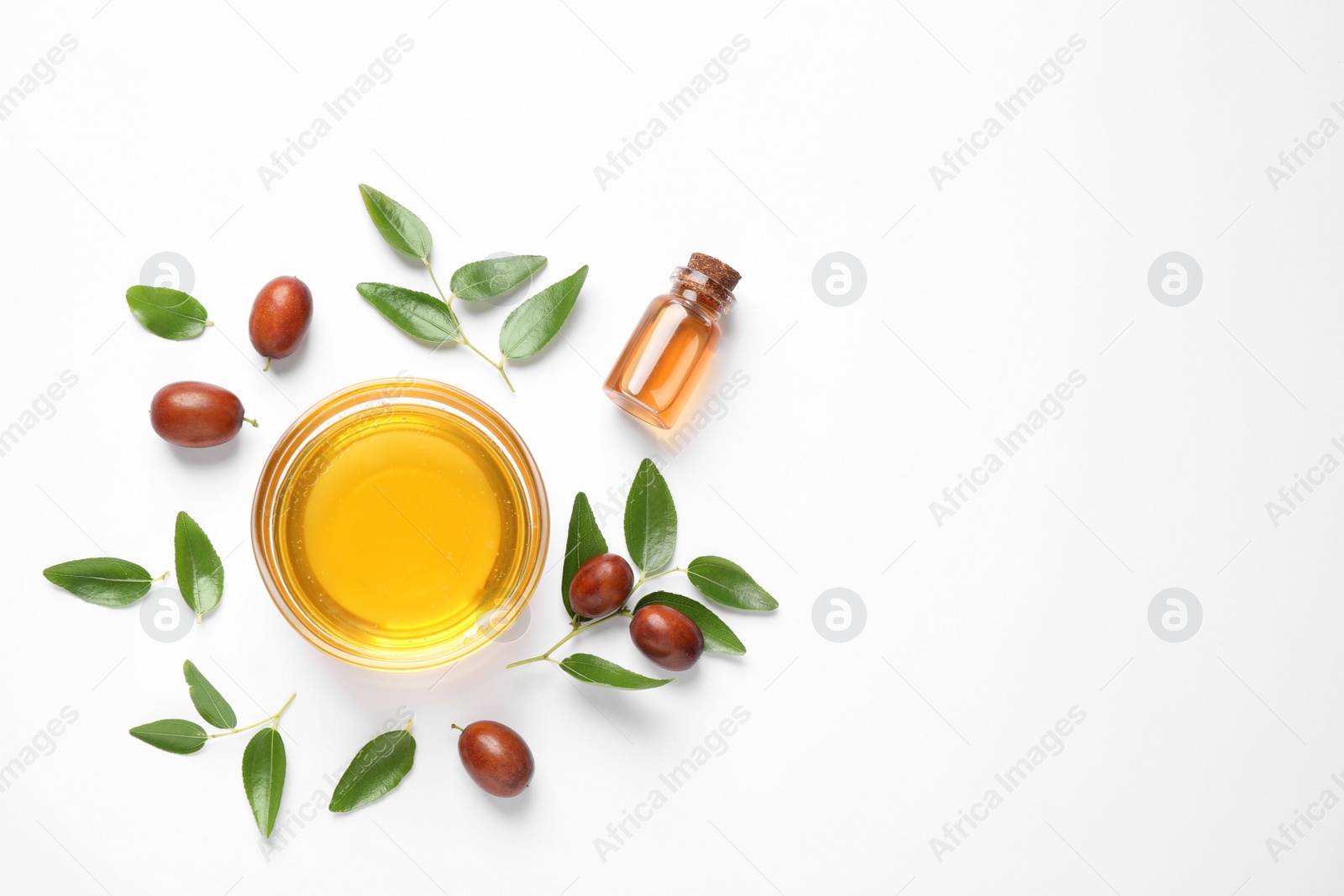 Photo of Bowl with jojoba oil and seeds on white background, top view