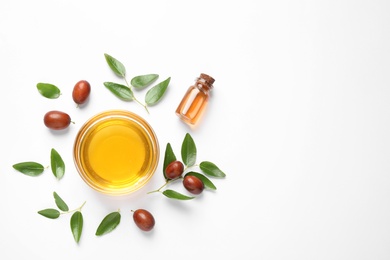 Photo of Bowl with jojoba oil and seeds on white background, top view