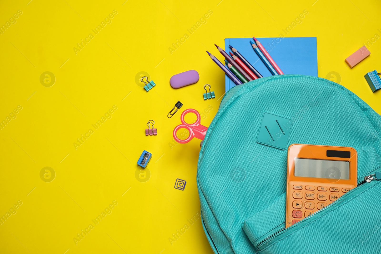 Photo of Stylish backpack with different school stationary on yellow background, top view. Space for text