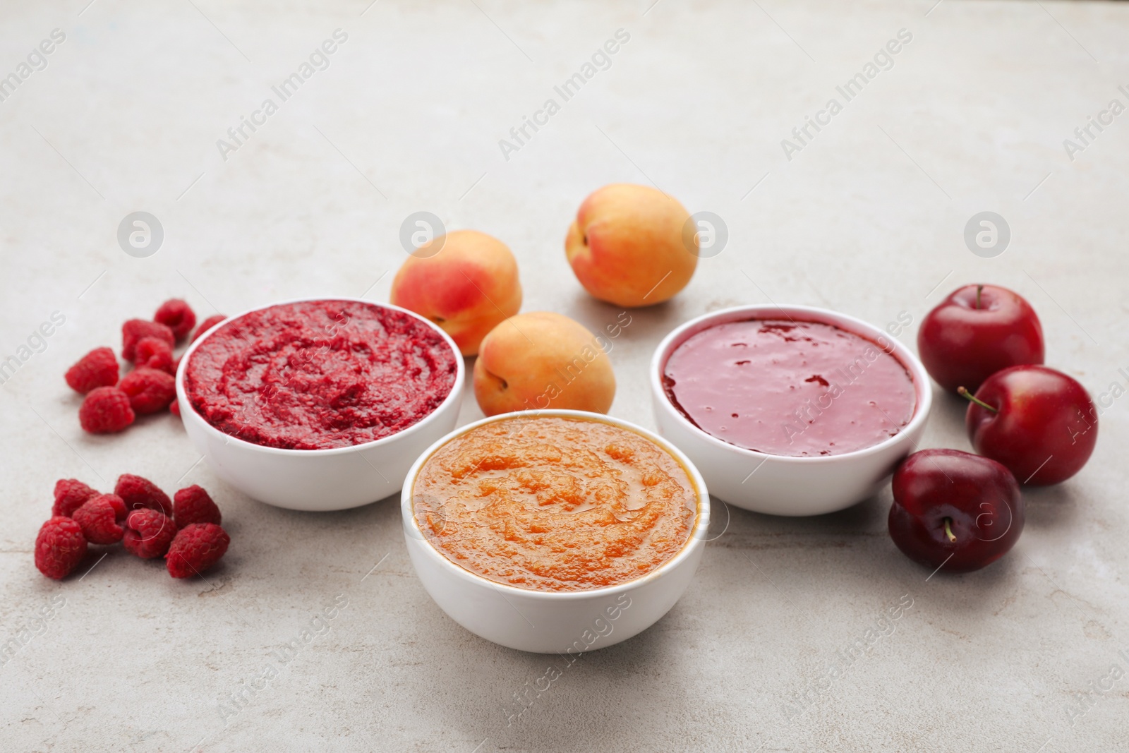 Photo of Different puree in bowls and fresh fruits on light grey table