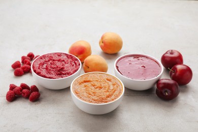 Photo of Different puree in bowls and fresh fruits on light grey table