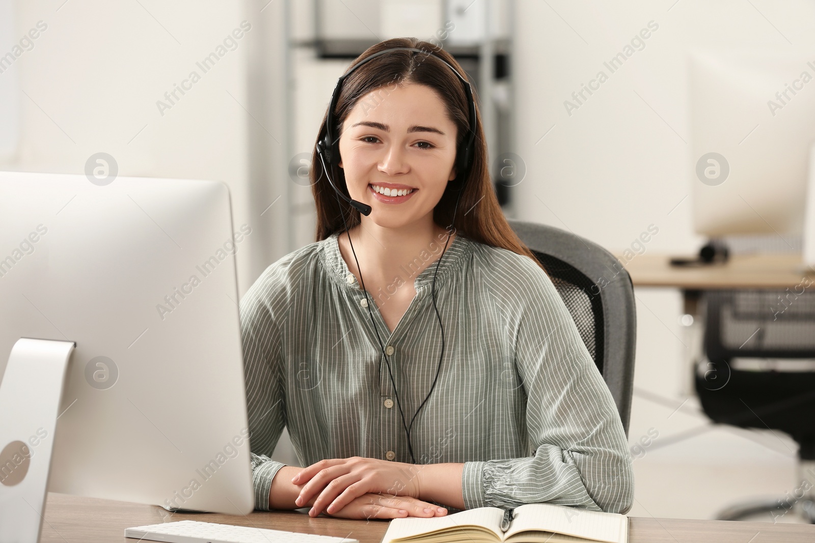 Photo of Hotline operator with headset working on computer in office