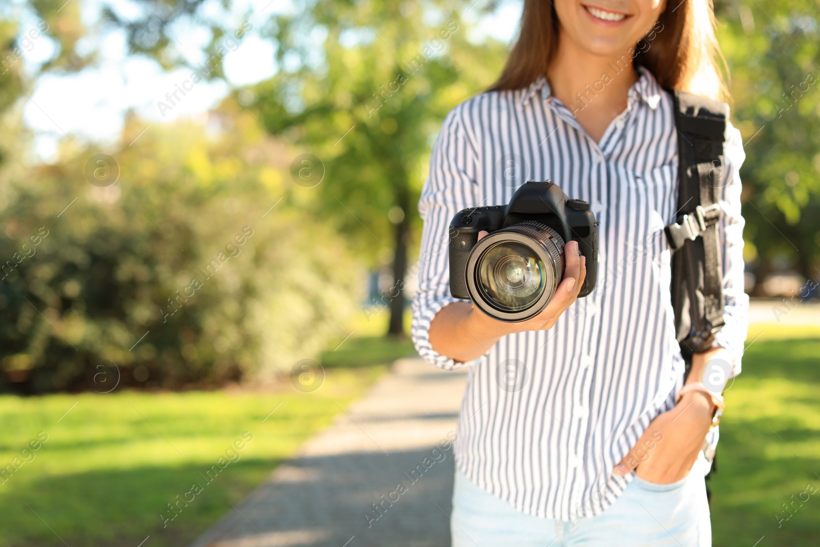 Photo of Young female photographer with professional camera in park. Space for text