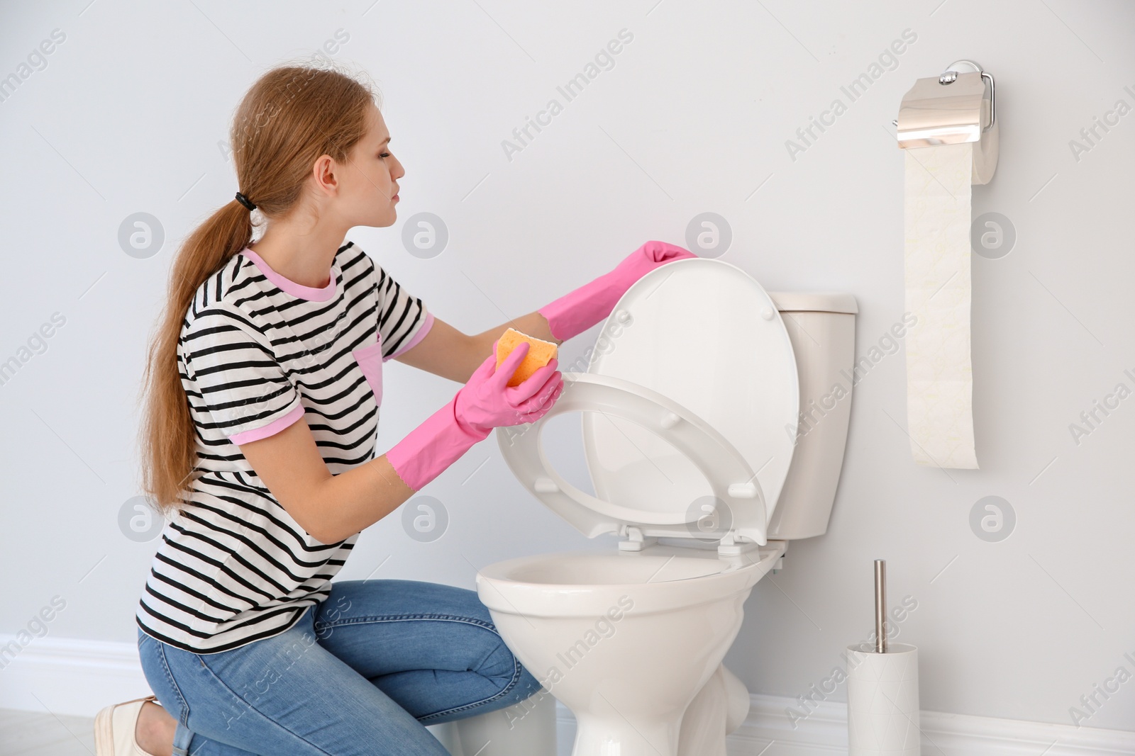 Photo of Woman cleaning toilet bowl in bathroom