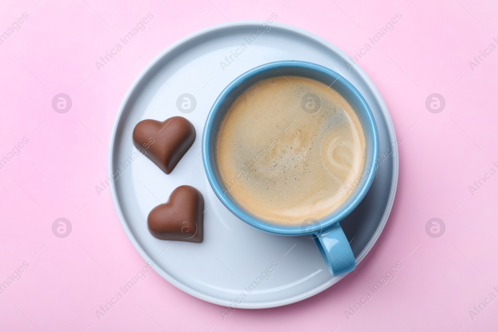 Photo of Romantic breakfast with cup of coffee and chocolate candies on pink background, top view. Valentine's day celebration