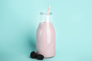 Tasty fresh milk shake and blackberries on light blue background