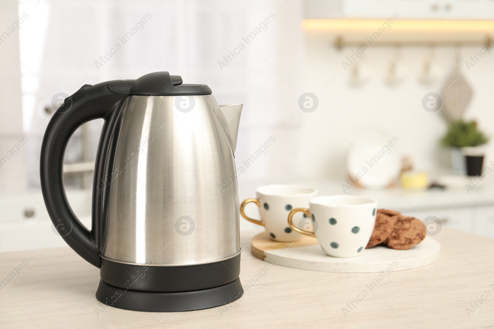 Photo of Modern electric kettle on table in kitchen. Space for text