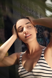 Photo of Woman washing hair in outdoor shower on summer day