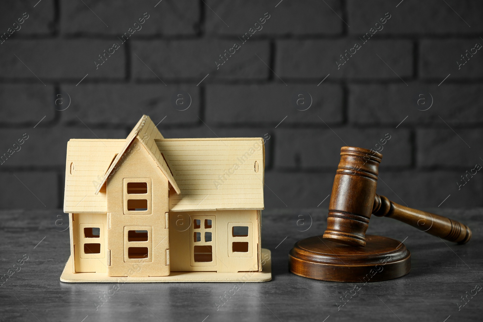 Photo of Construction and land law concepts. Judge gavel with house model on grey table