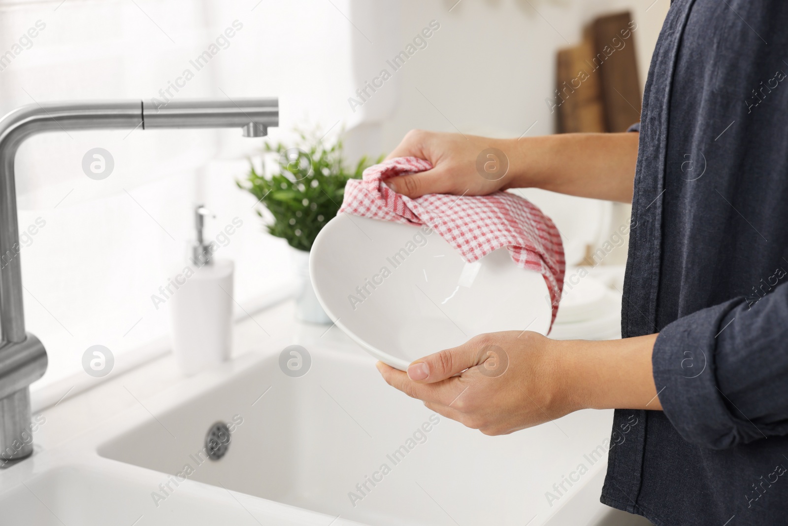 Photo of Woman wiping bowl with towel in kitchen, closeup