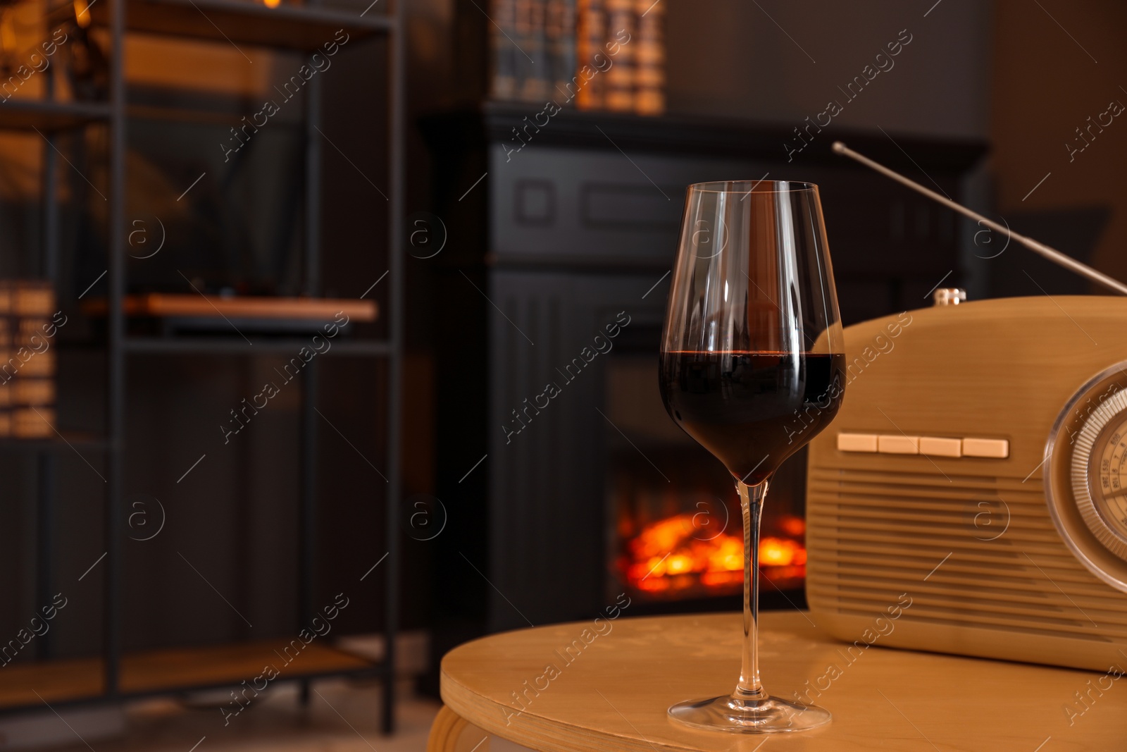 Photo of Glass of red wine and retro radio receiver on table in room, space for text. Relax at home