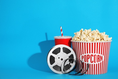 Popcorn, reel and drink on color background, space for text. Cinema snack