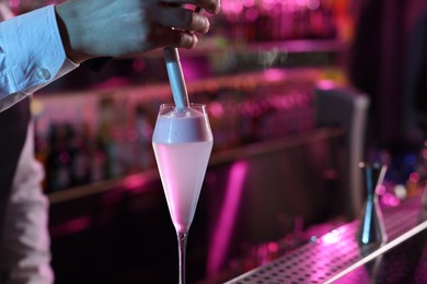 Photo of Bartender adding foam onto alcoholic cocktail at counter in bar, closeup. Space for text