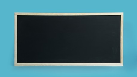 Photo of Clean black chalkboard on light blue background