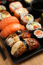 Photo of Set of delicious sushi rolls on mat, closeup