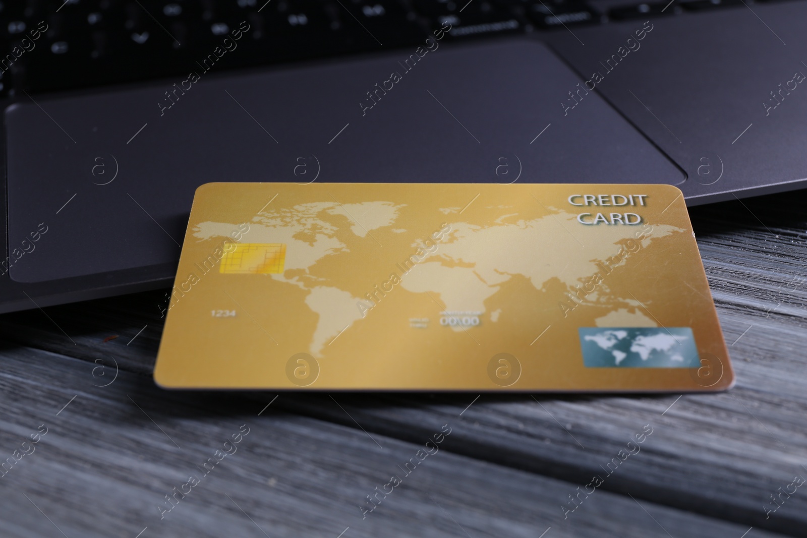 Photo of Credit card and laptop on grey wooden table, closeup
