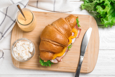 Tasty croissant sandwich with ham on white wooden table, flat lay