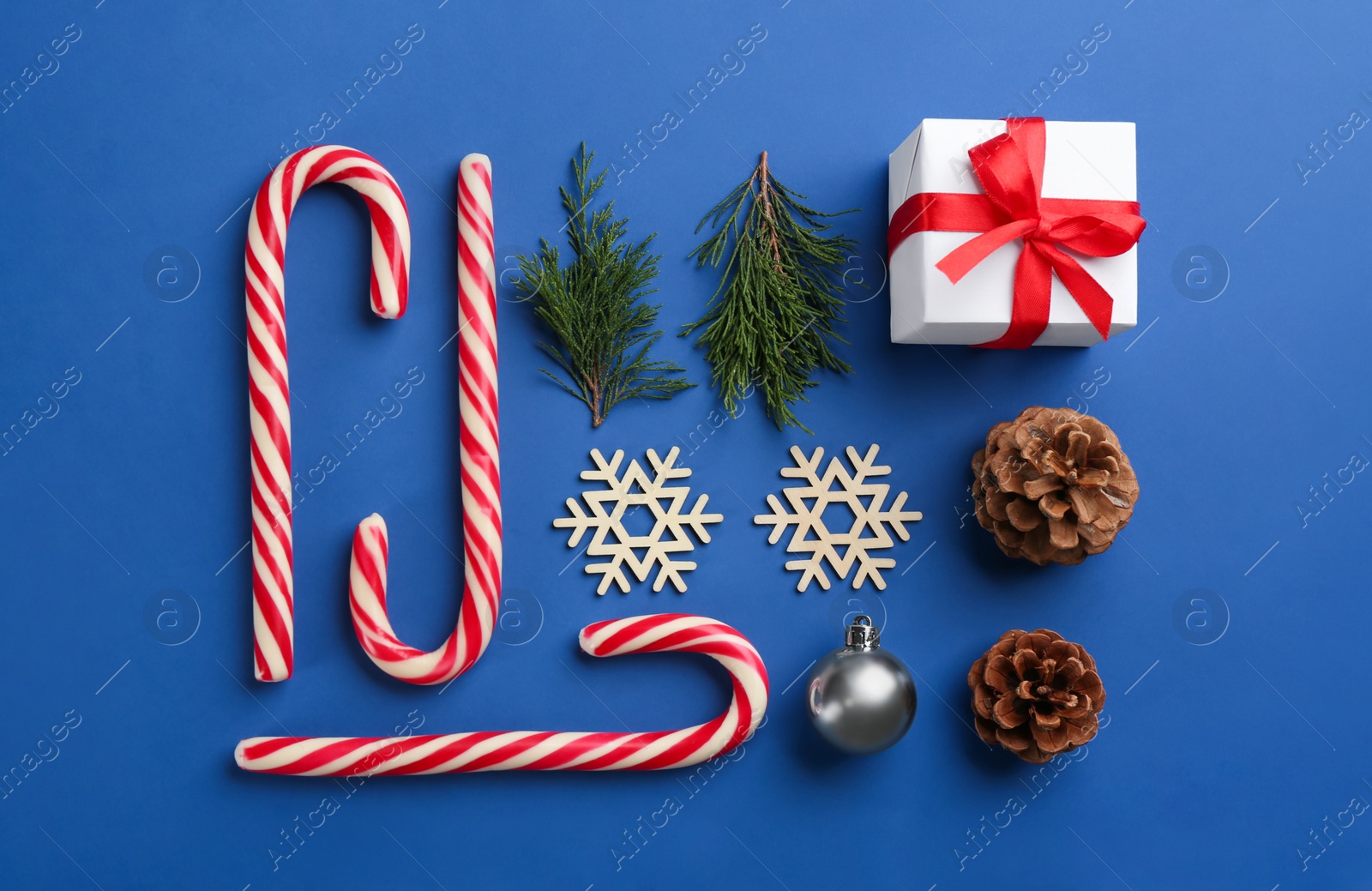 Photo of Flat lay composition with candy canes and Christmas decor on blue background