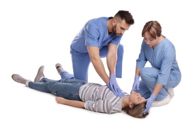 Photo of Medical workers in uniform performing first aid on unconscious woman against white background