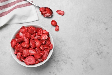 Photo of Bowl and spoon with dried strawberries on light grey table, flat lay. Space for text