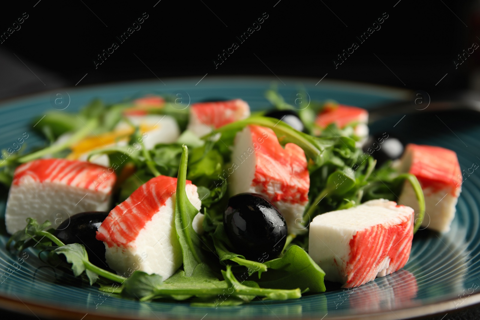 Photo of Delicious crab stick salad on blue plate, closeup