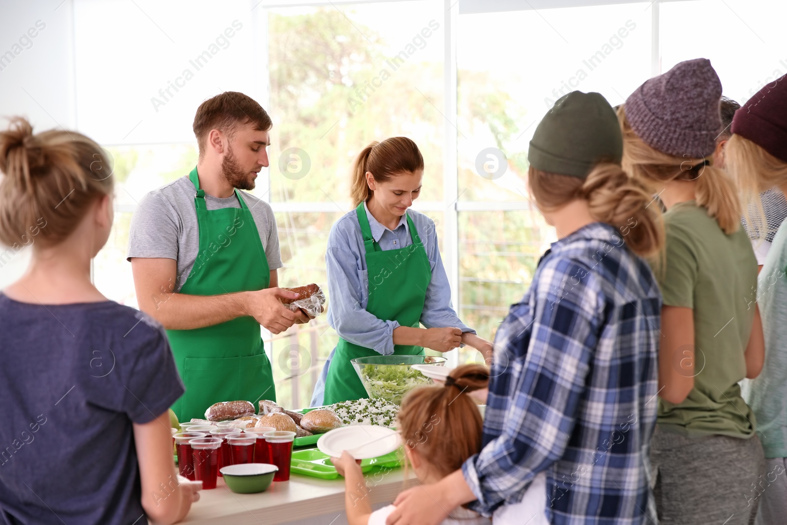 Photo of Volunteers serving food for poor people indoors