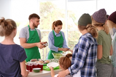 Photo of Volunteers serving food for poor people indoors