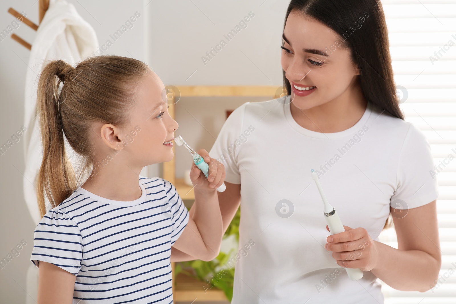 Photo of Mother and her daughter brushing teeth together in bathroom