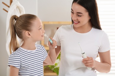 Mother and her daughter brushing teeth together in bathroom