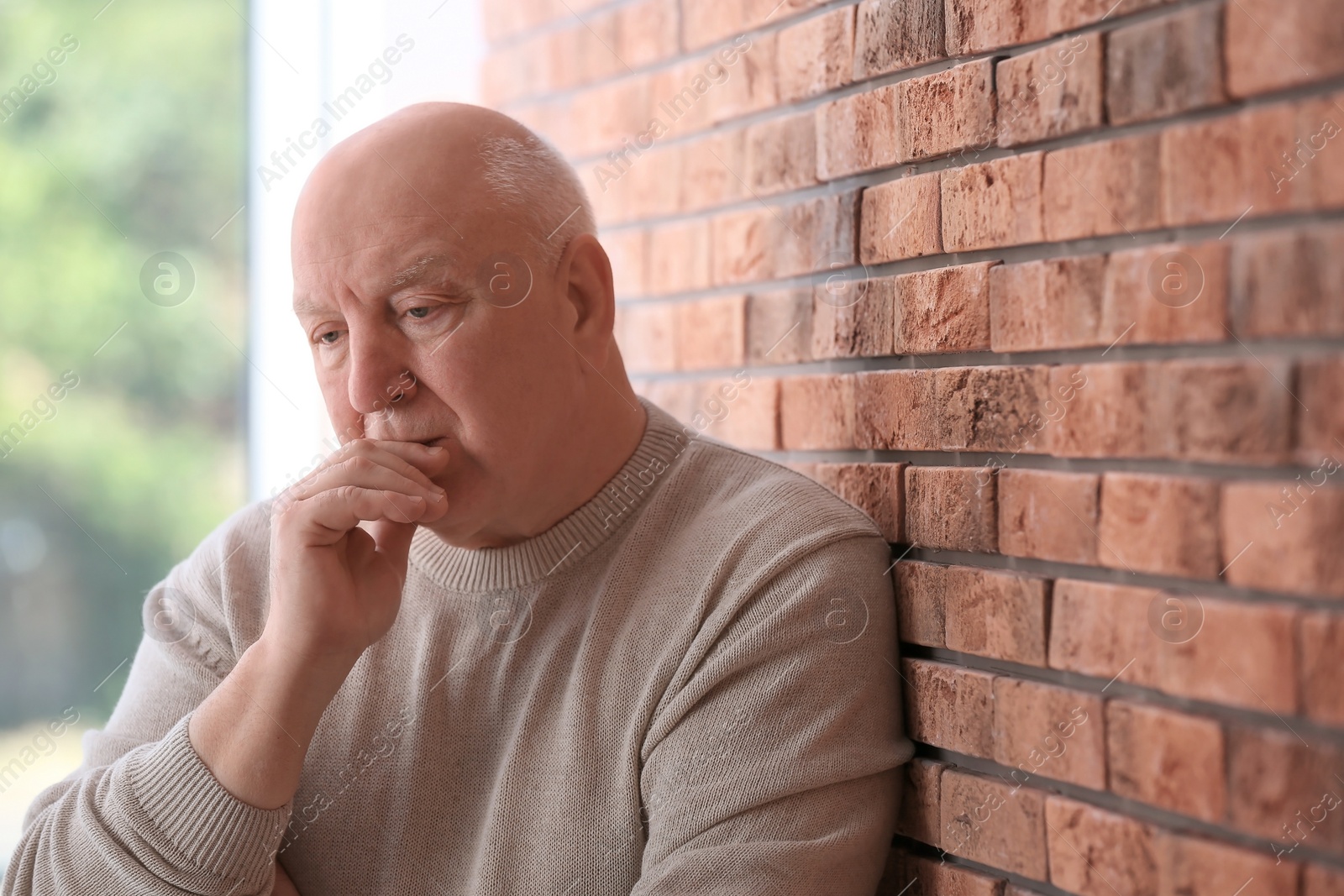 Photo of Senior man in state of depression near brick wall