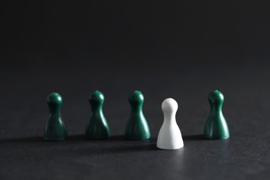 Photo of Choice concept. White pawn and green ones on dark table