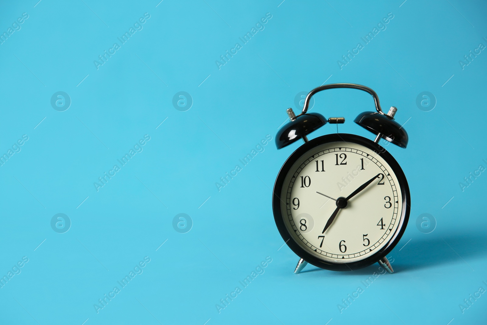 Photo of Alarm clock on light blue background, space for text. Morning time