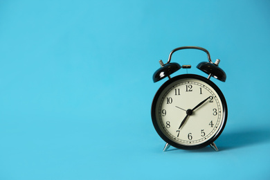 Photo of Alarm clock on light blue background, space for text. Morning time