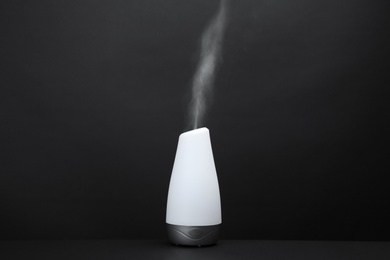 Modern aroma humidifier on black background. Space for text