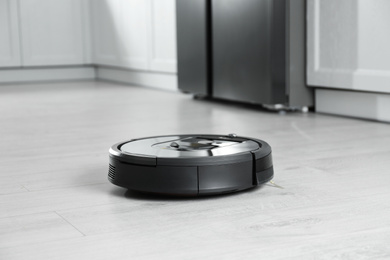 Photo of Modern robotic vacuum cleaner on floor in kitchen