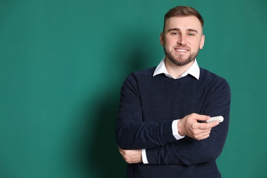 Photo of Portrait of young teacher with chalk on green background. Space for text