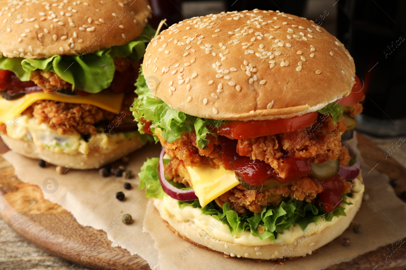 Photo of Delicious burgers with crispy chicken patty on wooden table, closeup