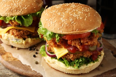 Photo of Delicious burgers with crispy chicken patty on wooden table, closeup