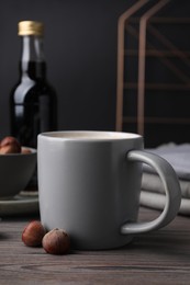 Mug of delicious coffee with hazelnut syrup on wooden table