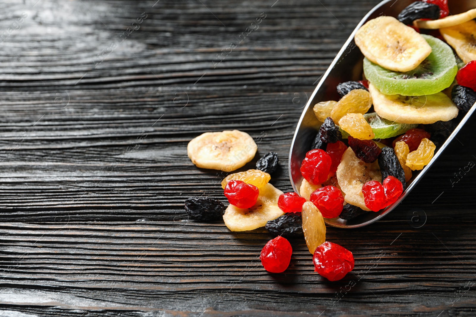 Photo of Scoop with different dried fruits on wooden background, space for text. Healthy lifestyle