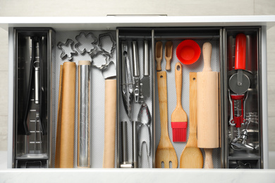 Photo of Different utensils in open desk drawer, top view